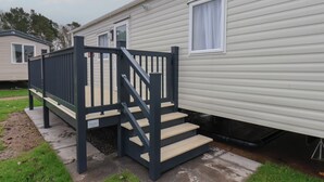 Una casa móvil con una escalera de madera que lleva a una terraza.