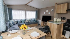 Un espacio habitable compacto con zona de comedor, kitchenette y sofá con cojines estampados.