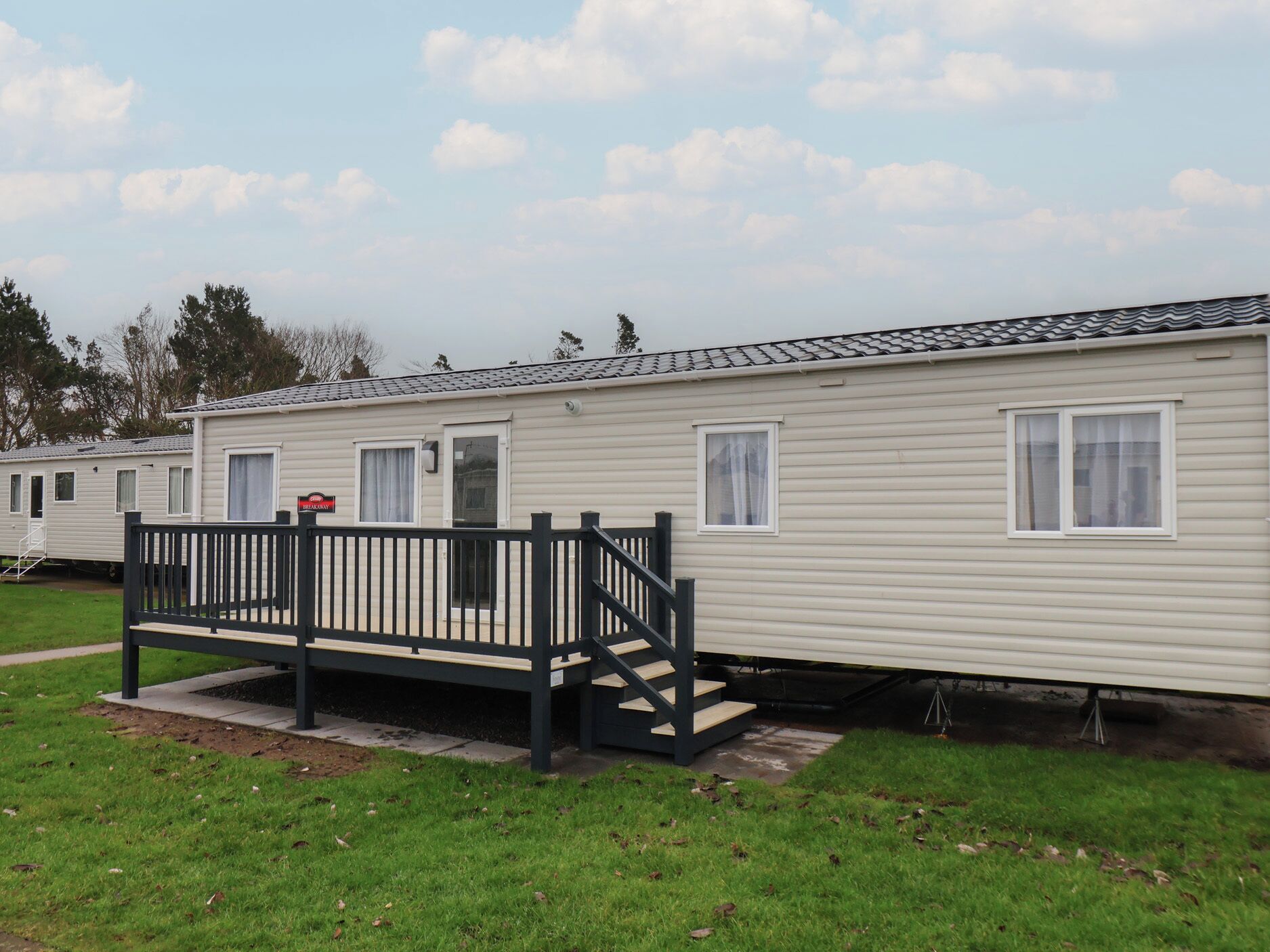 A mobile home with a front porch and a small staircase leading to the entrance.