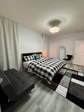 Ein modernes Schlafzimmer mit Bett, einer Bank, einem Spiegel und einer Tür.