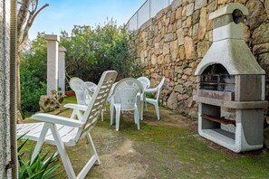 An outdoor seating area with white plastic chairs and a stone wall. - Apartment 'Quadrilocale Le Colonne' with Sea View, Private Terrace and Air Conditioning (Li Mori)