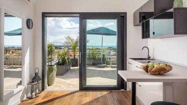 Une cuisine moderne avec vue sur la mer, une porte-fenêtre coulissante et un petit coin repas.