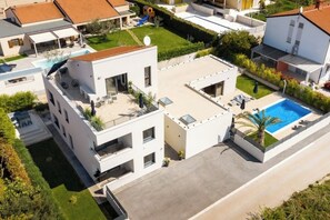 A modern multi-story residential building with a rooftop terrace, a swimming pool, and a well-maintained garden. - Soulshine Belvedere Holidays – Modern Studio with Adriatic Views & Terrace (Novigrad)