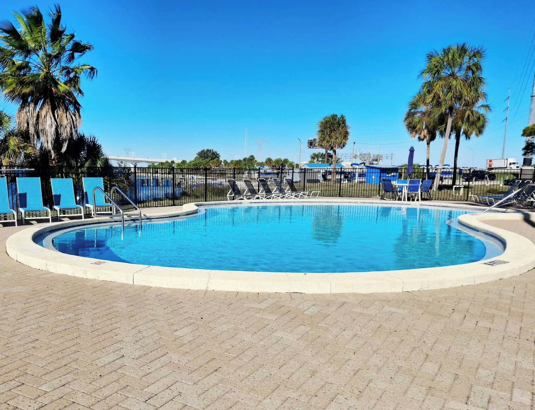 A swimming pool with lounge chairs and palm trees.