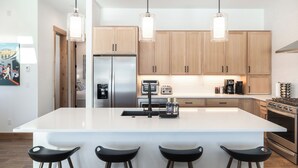 A modern kitchen with a central island, stainless steel appliances, wooden cabinets, and pendant lighting. - Spacious Retreat II Fireplace, Hot Tub, Free Bus, 2 Master Bedrooms (Fraser)