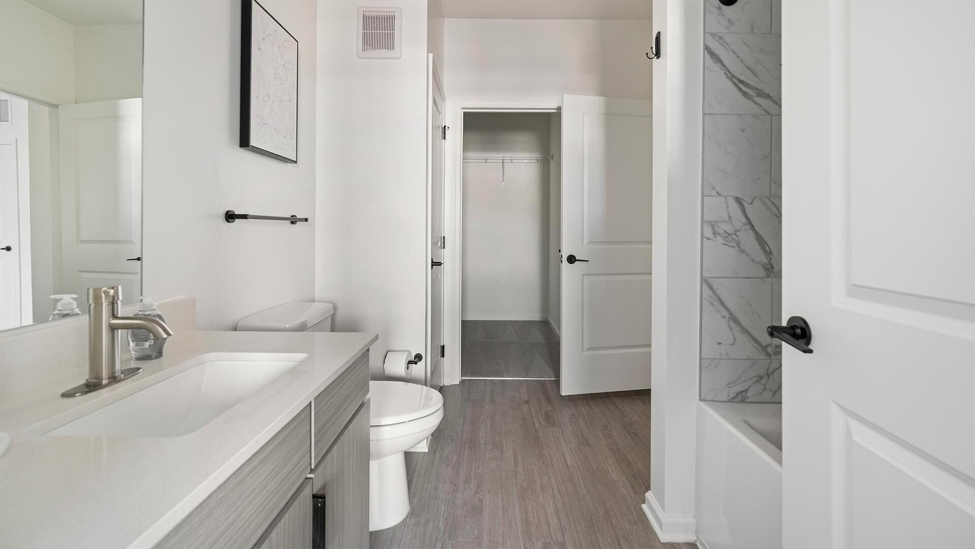 Un bany modern amb un lavabo, vàter i zona de dutxa de color blanc.