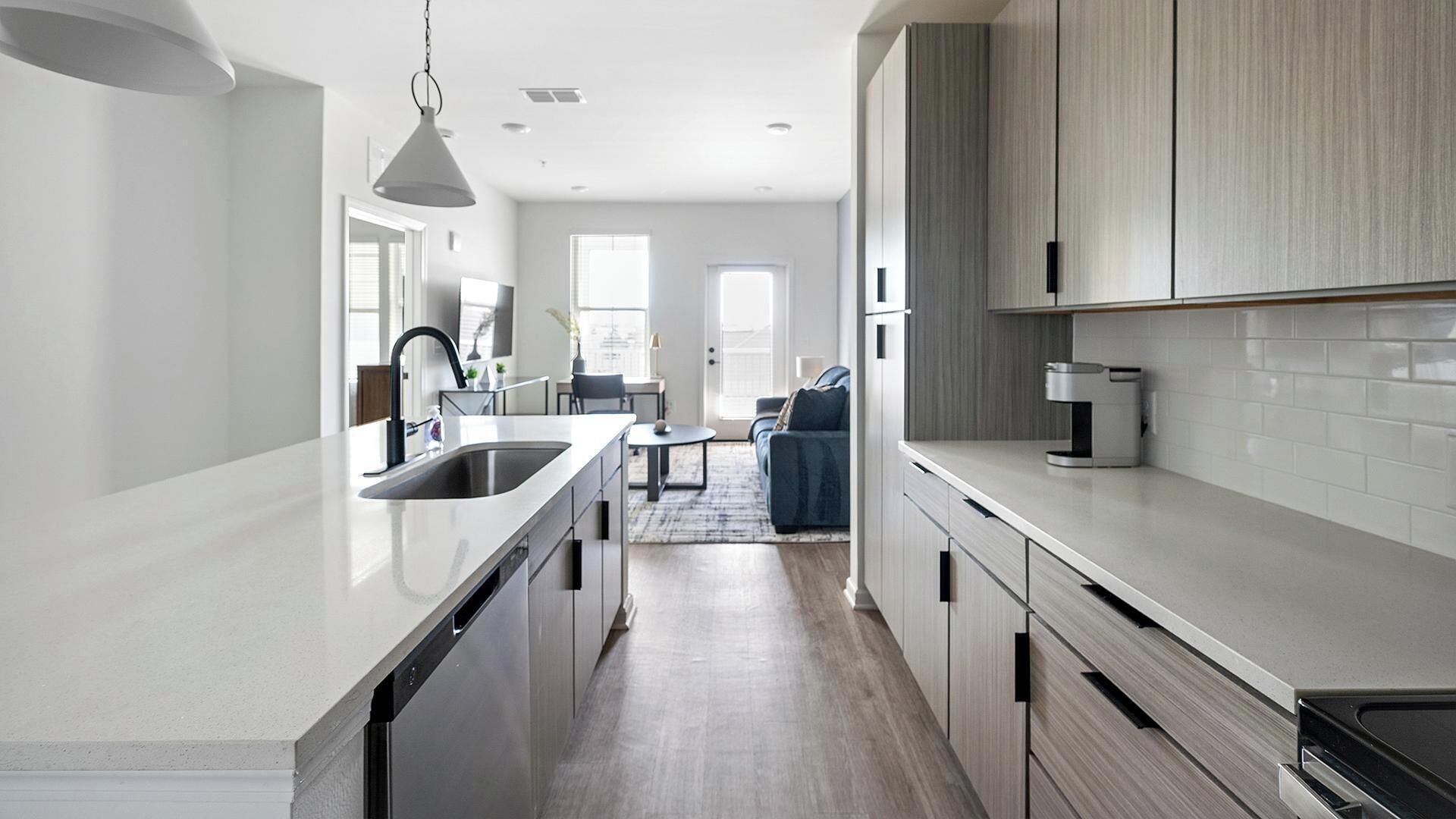 A modern kitchen with a central island, a dining area with a table and chairs, and a living space with a sofa.