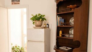 A kitchen with a white refrigerator, a wooden cabinet with dishes, and a sign indicating no smoking. - Laura's little houses: second floor 2 (Palermo)