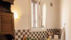 A compact kitchen with a gas stove, a sink, and a window with blinds. - Laura's little houses: second floor 2 (Palermo)