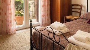 A bedroom with a bed, a chair, a wardrobe, and a window with curtains. - Laura's little houses: second floor 2 (Palermo)