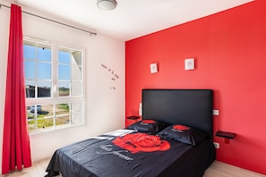 A bedroom with a bed, a window, a red wall, and a view of the outside. - Holiday Home 'Gîte De L'orchidée' with Private Terrace, Private Garden and Wi-Fi (Saint-Epain)