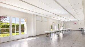 Une pièce spacieuse avec une longue table, de grandes fenêtres et une vue sur la verdure environnante.
