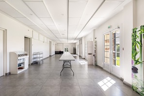A spacious hallway with a long table, a vending machine, and a cart. - Holiday Home 'Gîte De L'orchidée' with Private Terrace, Private Garden and Wi-Fi (Saint-Epain)