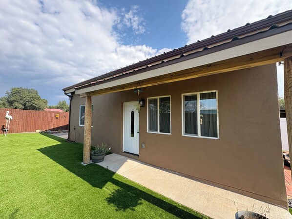 Einbungalow mit brauner Fassade, einer weißen Tür und zwei Fenstern.