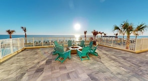 A terrace with a fire pit, outdoor seating, and a view of the ocean. - Landing | Amazing 2BD, Gym, Clubhouse (Daytona Beach)