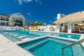 Zona de piscina amb gandules i una construcció amb teulada de palla.