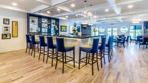 Un espace bar moderne avec un comptoir haut, des tabourets de bar et un lustre.