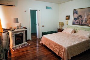 A bedroom with a bed, a fireplace, a green bench, and a painting on the wall. - Villa Letizia (Chieti)