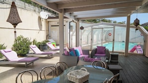 A covered outdoor area with lounge chairs, a table, and a glass-enclosed pool. - Villa Letizia (Chieti)