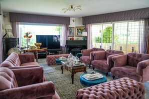 A living room with a piano, plush pink sofas, a coffee table, and a television. - Villa Letizia (Chieti)