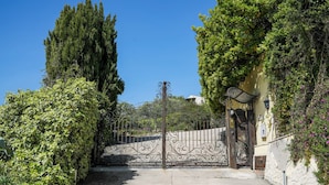 A gated entrance with a wrought iron gate, surrounded by lush greenery and a stone wall. - Villa Letizia (Chieti)