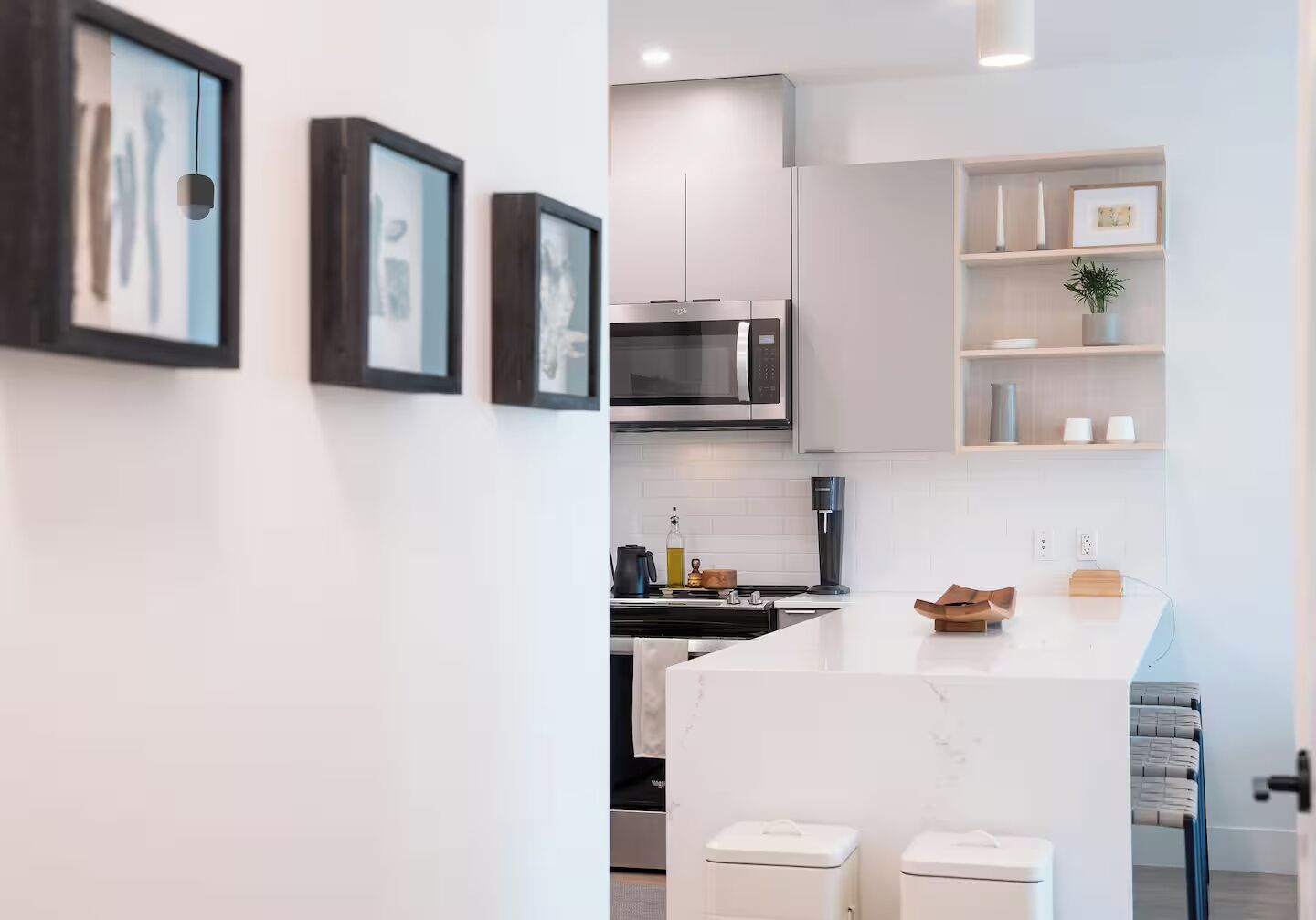Une cuisine moderne avec des meubles blancs, un four à micro-ondes encastré et un îlot central doté de tabourets.