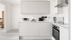 Eine moderne Küche mit weißen Schränken, einem Einbauofen, einer Mikrowelle und einer Kaffeemaschine.