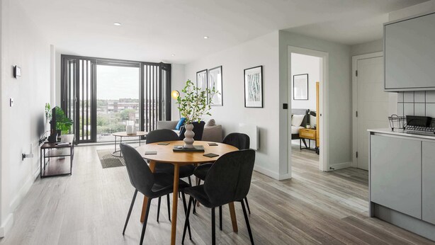 Ein modernes Wohnzimmer mit einem runden Esstisch, schwarzen Stühlen und einem großen Fenster mit Blick auf die Stadt.