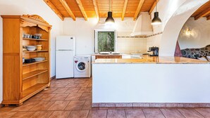 Ett kök med synliga träbjälkar, en tvättmaskin och en stor köksö.