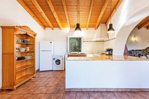 Eine Küche mit Holzbalken, einer Waschmaschine und einer großen Kochinsel.