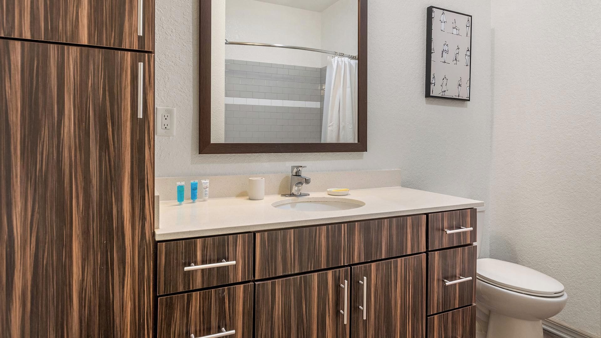 A bathroom with a wooden vanity, a sink, a mirror, and a toilet.