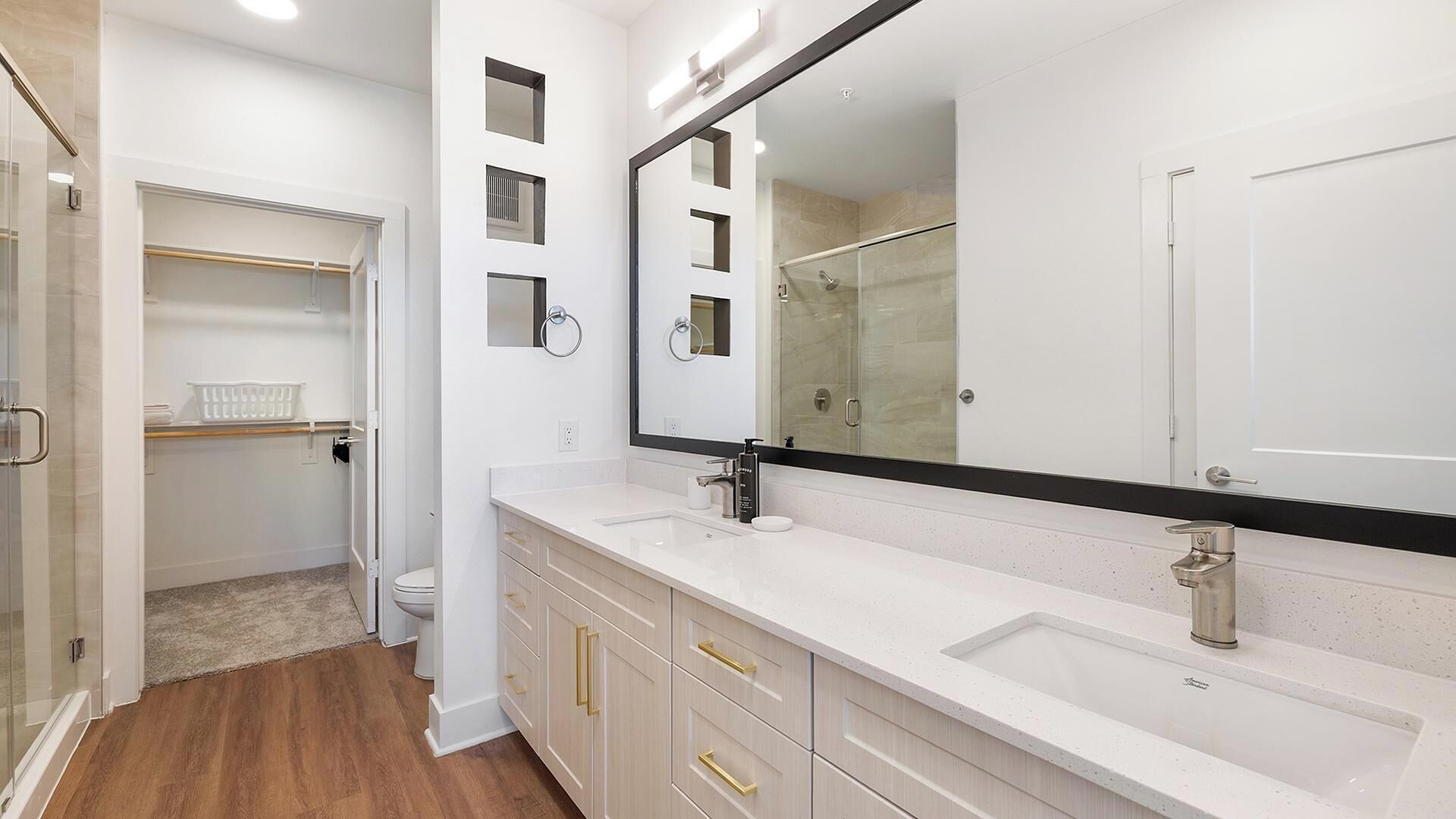 A modern bathroom with a large mirror, a walk-in shower, and a walk-in closet.