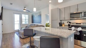 A modern kitchen with a granite countertop, stainless steel appliances, and a bar stool area.