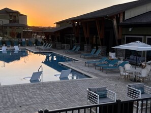 A pool area with lounge chairs and umbrellas, surrounded by buildings with stone and wooden architecture. - 3 BR 2 Bath Townhouse w 2 car garage (Pelham)