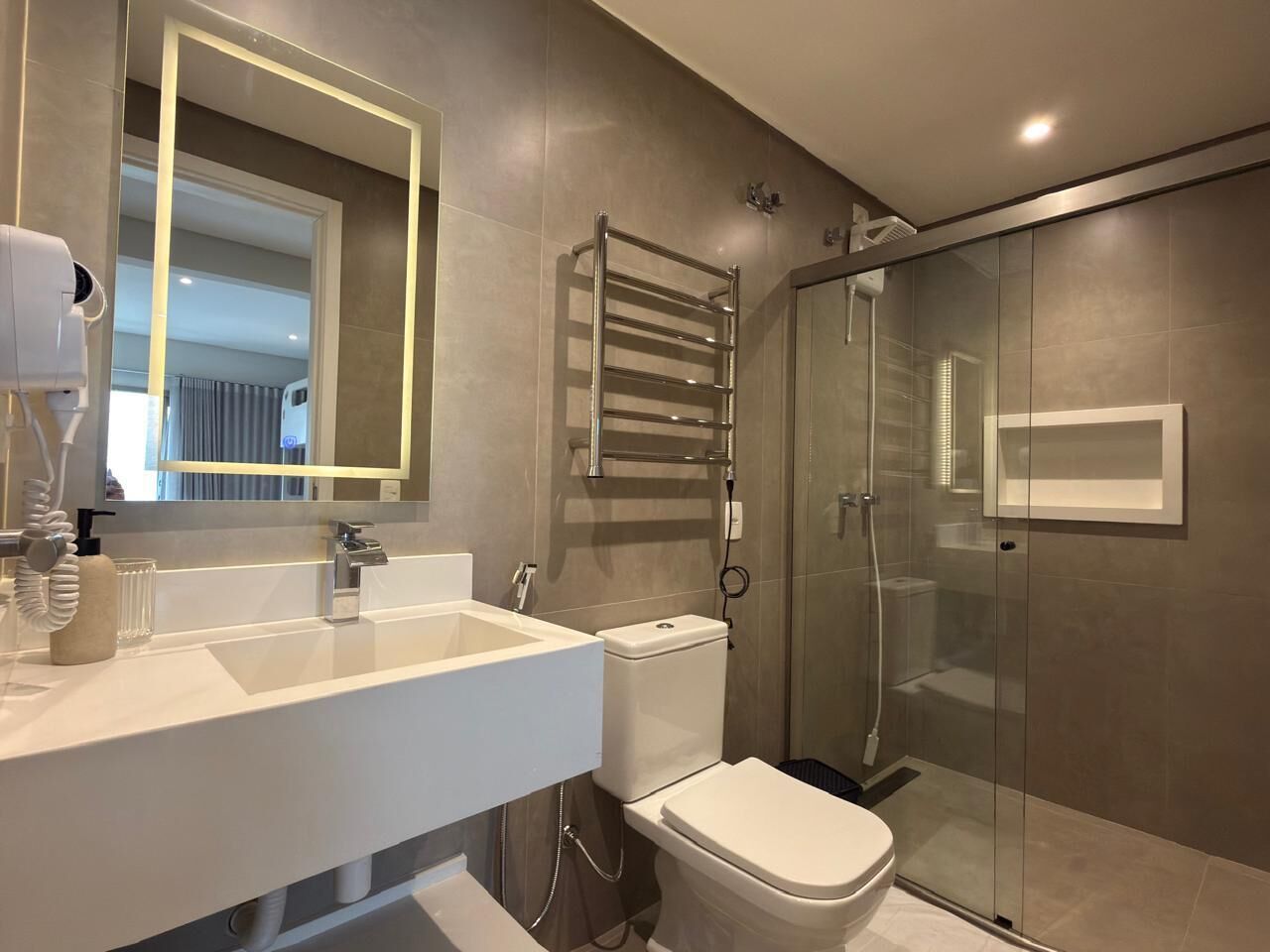 A modern bathroom with a white sink, a toilet, and a glass-enclosed shower.