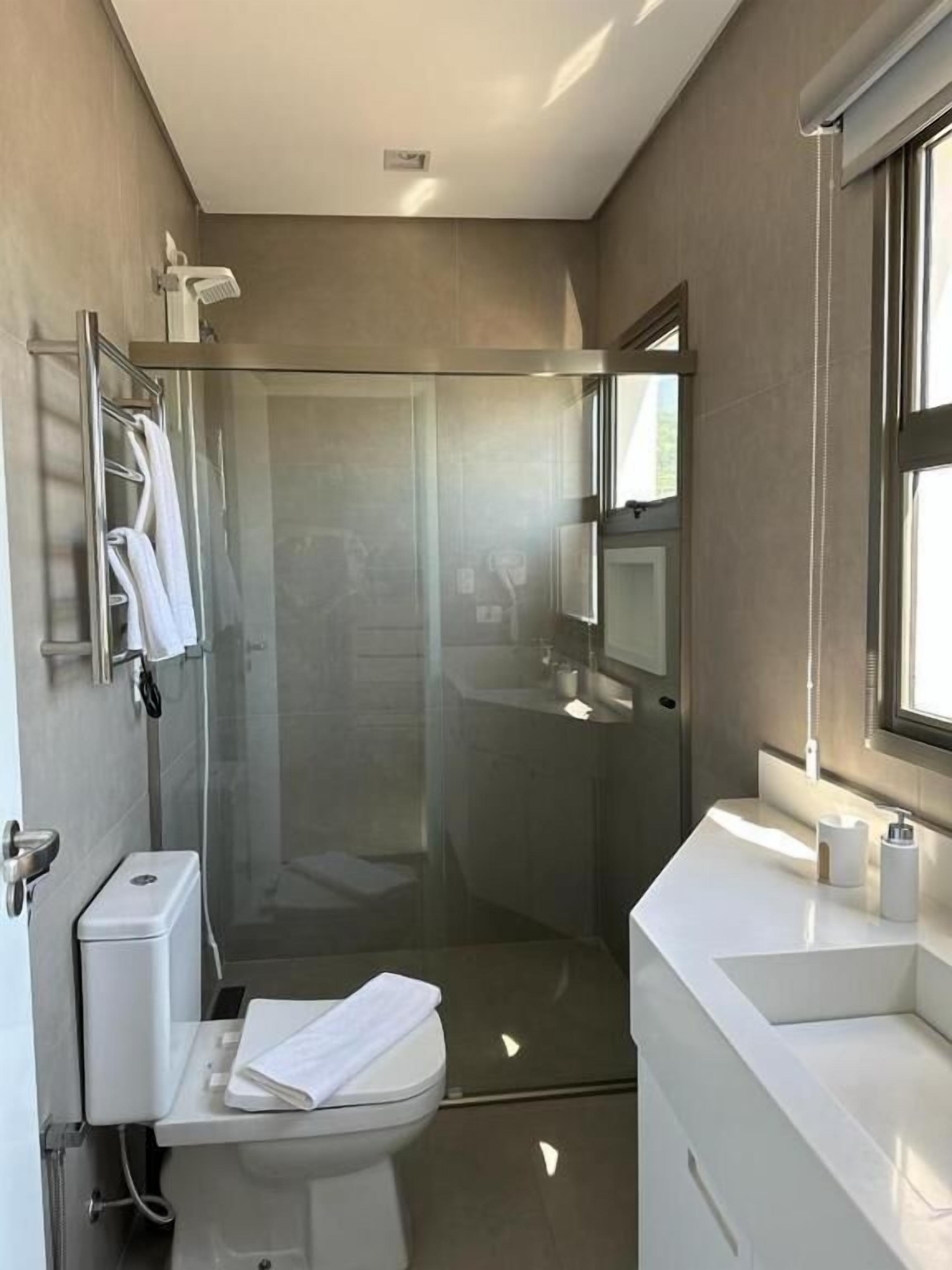 A modern bathroom with a glass-enclosed shower, a toilet, and a sink.