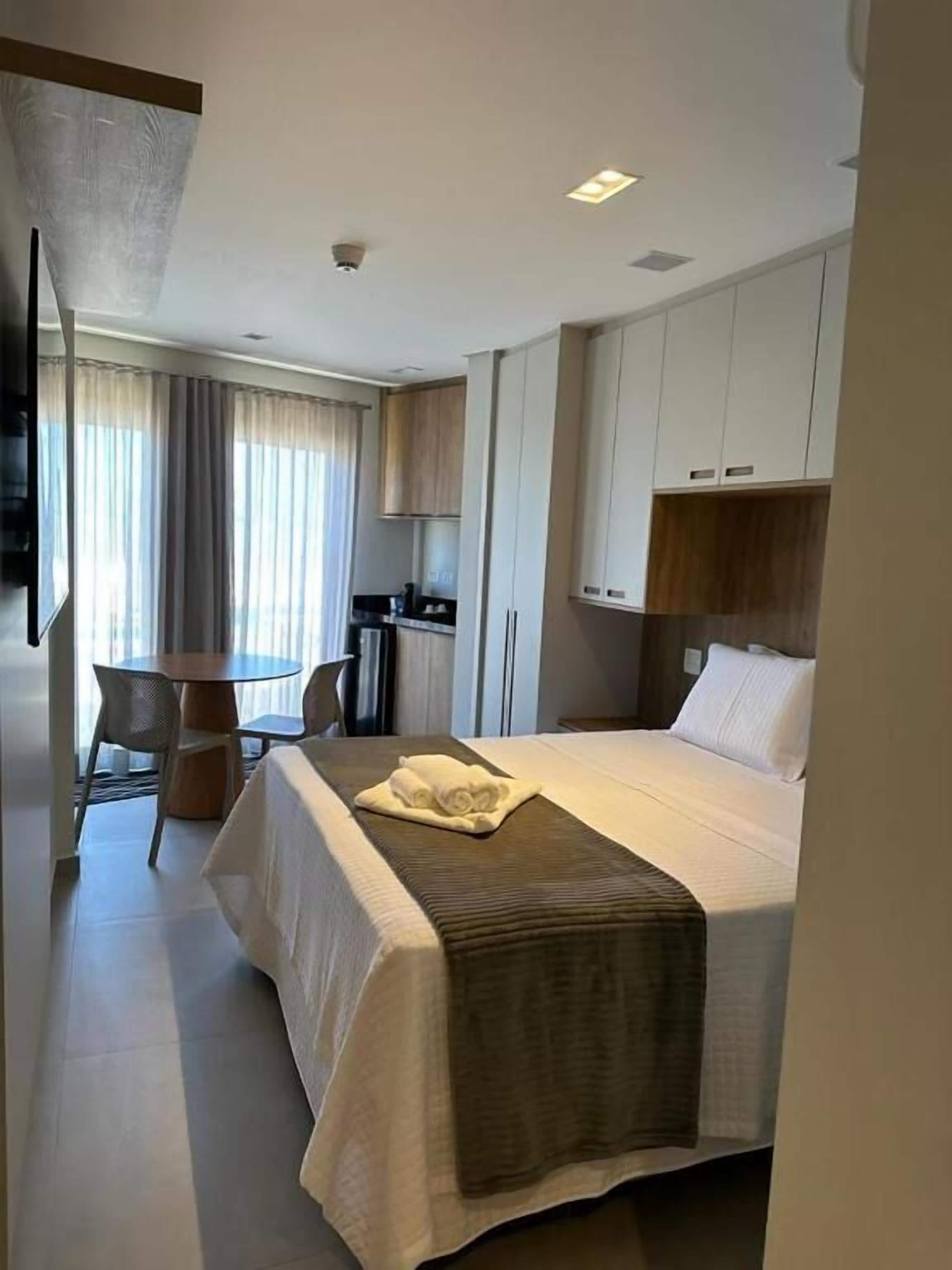 A hotel room with a bed, a desk, and a kitchenette.
