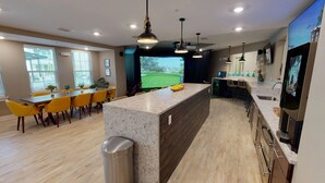 Una cocina moderna con una isla central, un comedor con sillas amarillas y un amplio ventanal con vistas a un campo de golf.