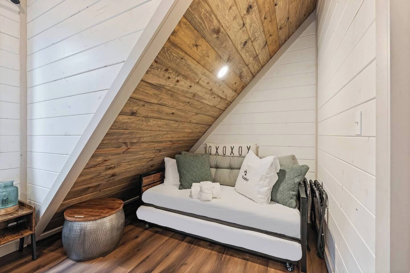 Ein Schlafzimmer im Loft-Stil mit Schrägwand, einem weißen Sofa und Holzboden.