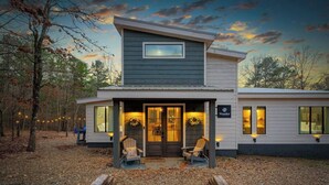 Un chalet à deux étages doté d’une véranda, d’une enseigne sur laquelle on peut lire « Wander » et offrant une vue sur la forêt environnante.