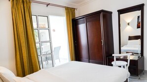 Ein Hotelzimmer mit Bett, Kleiderschrank, Schreibtisch und Stuhl.