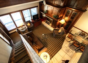 A spacious living area with a fireplace, comfortable seating, and a staircase leading to an upper level. - 1-Bed Loft Condo w/ Full Kitchen + Hot Tub Access (Steamboat Springs)