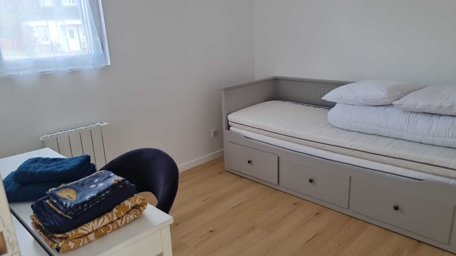 A bedroom with a bed, a desk, and a chair.