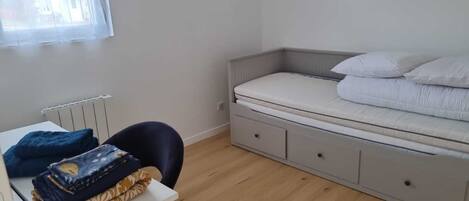 A bedroom with a bed, a desk, and a chair.