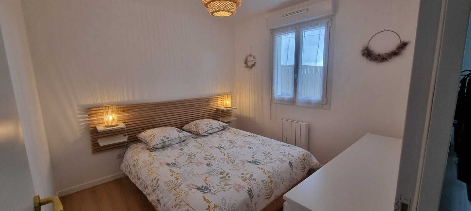 Une chambre à coucher avec un lit, des lampes de chevet, une fenêtre et un radiateur.