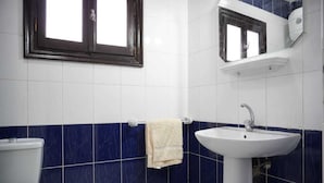 Une salle de bain avec des toilettes blanches, un lavabo et un porte-serviettes.