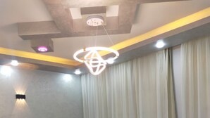 Una camera da letto con un letto, comodini, una lampada a sospensione e una finestra con tende.