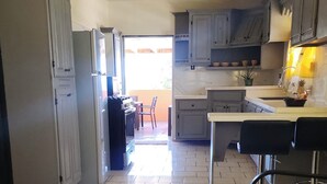 A kitchen with cabinets, a refrigerator, a dining table, and a bar area.