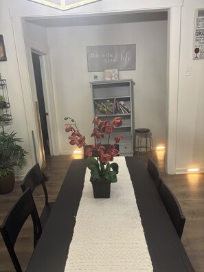 A dining area with a table set for four, a potted orchid centerpiece, and a bookshelf in the background. - Westside Family home and small dog friendly in Atlanta. (Atlanta)