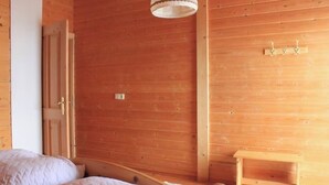 Une pièce en bois avec un lit, une petite table et un luminaire suspendu.